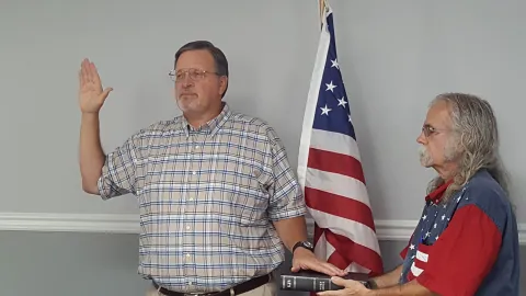 Mayor Gary Chandler has his right hand raised and is reciting the oath of office with Vice Mayor is holding a Bible with the Mayor's left hand lying on the Bible.