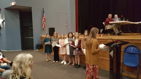 A group of students talking to the school board members about leadership.