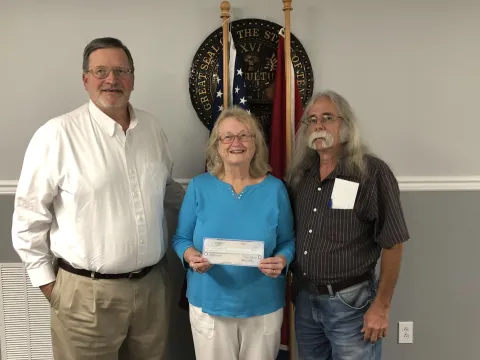 Picture of two males with a female in between.  The female is holding a check.  The males are the mayor and vice mayor of Plainview City.  Plainview made a donation to Imagination Library