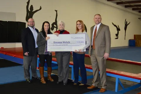 Breann Welch (second from left) of Sweet Southern Tumbling receives a small business loan check from Clinch Powell.