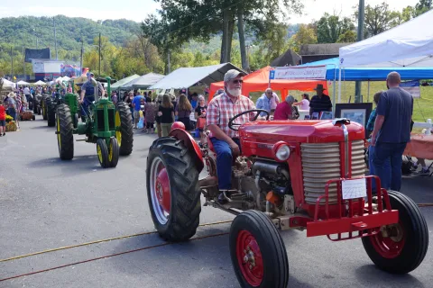 An antique tractor in a parade at a festival