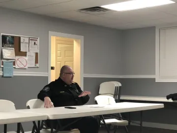 Policeman seated and speaking at a meeting