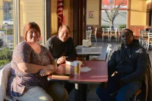 The Rev. Kathy Chesney, Fr. Steve Pawelk and Josiah Kimani gather for prayer and Bible study at Hardee's in Maynardville.