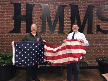 Keith Kail, WoodmenLife sales rep and Lodge 1072 Vice President, presents an American flag to HMMS Principal Greg Clay.